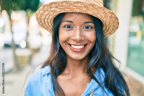 Young beautiful indian woman wearing summer hat smiling happy walking at the city. © Krakenimages.com
