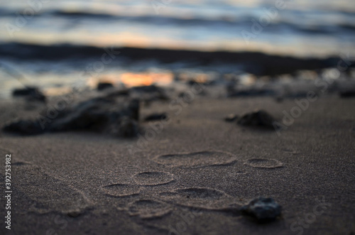 Huellas de gotas en la arena a la orilla del río al atardecer	