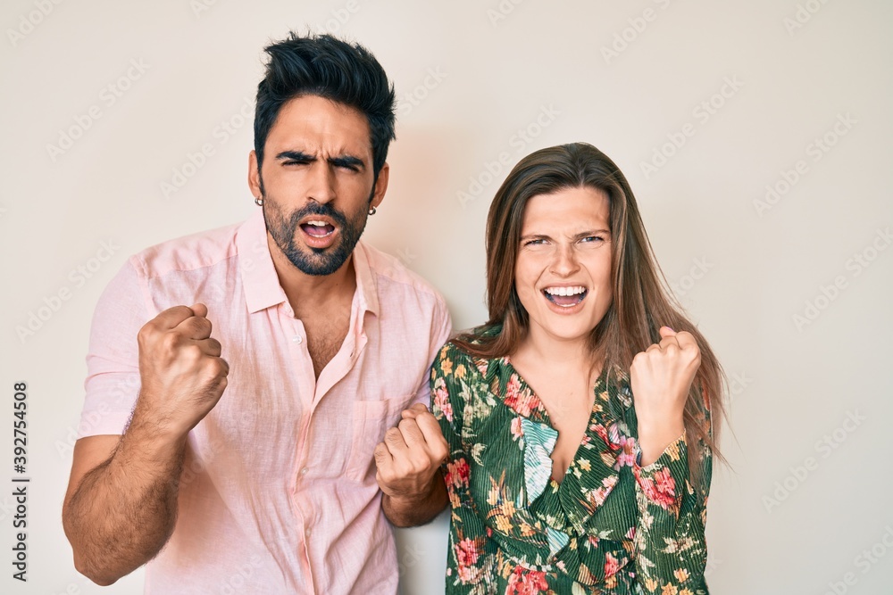 Beautiful young couple of boyfriend and girlfriend together angry and mad raising fist frustrated and furious while shouting with anger. rage and aggressive concept. Beautiful young couple of boyfriend and girlfriend together angry and mad raising fist frustrated and furious while shouting with anger. rage and aggressive concept.