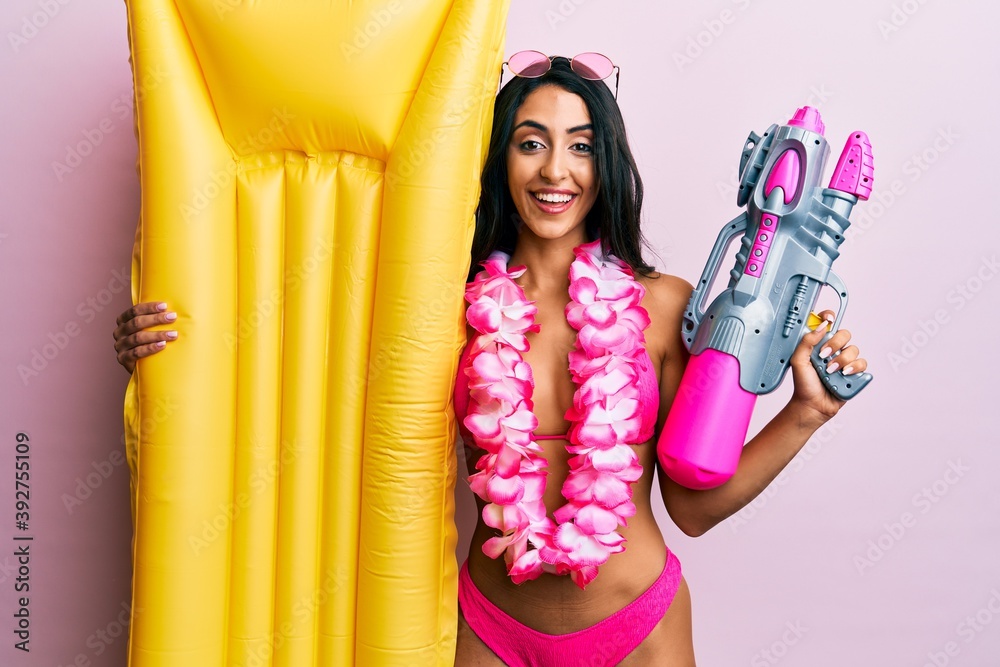 Obraz premium Beautiful hispanic woman wearing swimsuit and holding summer float smiling and laughing hard out loud because funny crazy joke.