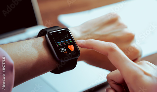 Fototapeta Naklejka Na Ścianę i Meble - Close up of hand touching smartwatch with health app on the screen, gadget for fitness active lifestyle.