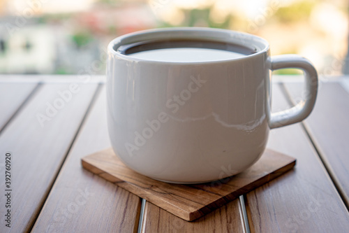 White cup of black coffee on a wooden table.