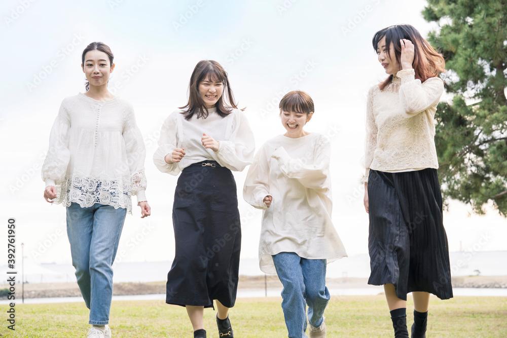 笑顔で話しながらゆっくり走る女性4人 笑顔で話しながらゆっくり走る女性4人