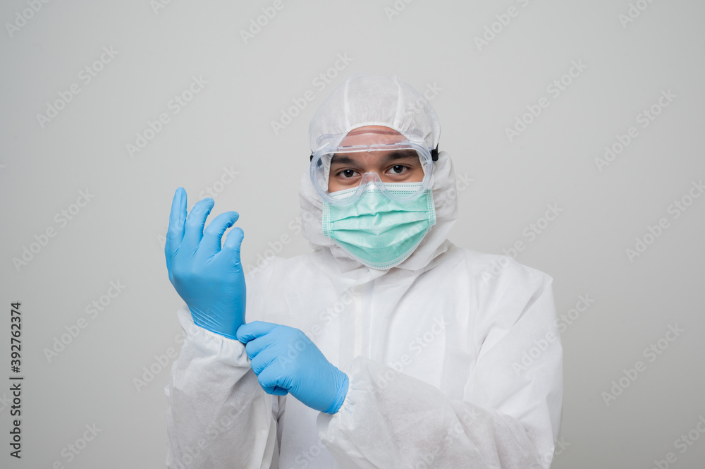 A portrait of virologist put on PPE suit wearing blue glove look into camera isolated on white background. Personal Protective Equipment Concept.. A portrait of virologist put on PPE suit wearing blue glove look into camera isolated on white background. Personal Protective Equipment Concept..