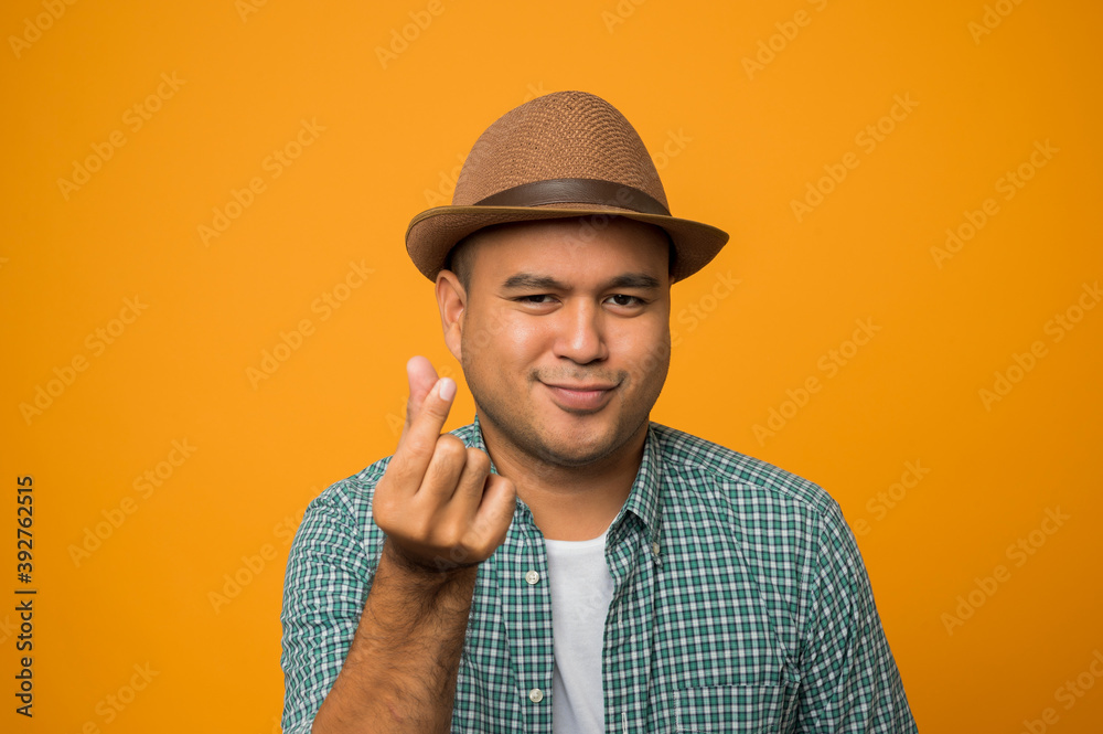 Handsome tourist man on vacation posing mini heart with smiling and happiness isolated on yellow background. Handsome tourist man on vacation posing mini heart with smiling and happiness isolated on yellow background.