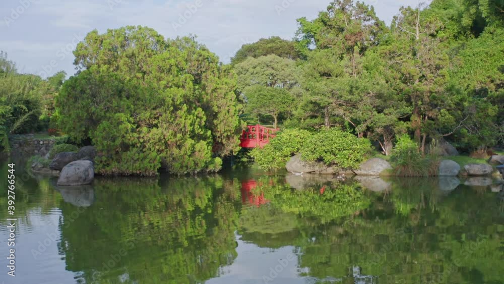 Low-angle view of red bridge at Japanese garden seen from pond. Santo Domingo Low-angle view of red bridge at Japanese garden seen from pond. Santo Domingo