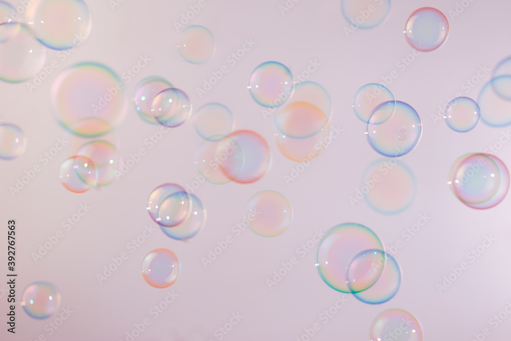 Beautiful shiny colorful soap bubbles floating on soft pink texture background. Abstract, Natual fresh summer background.