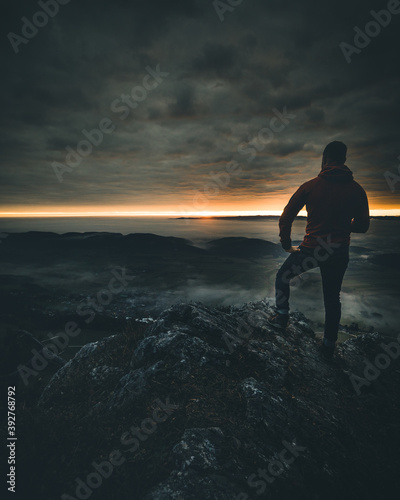 man on mountain top watching the sunset