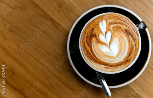 Top view of fresh brewed coffee with beautiful latte art on wooden table in cafe with copy space. Coffee break recreation relaxation