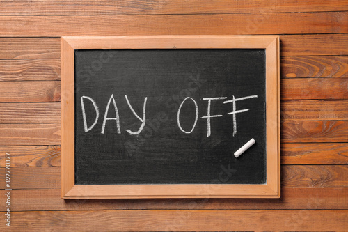 Chalkboard with text DAY OFF on wooden background