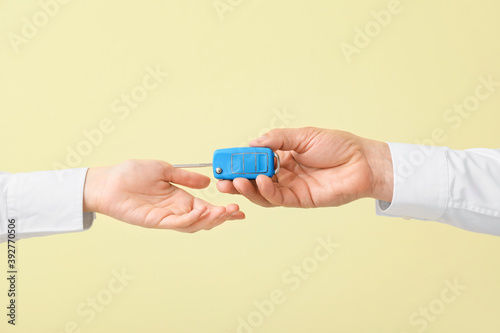 Male and female hands with car key on color background
