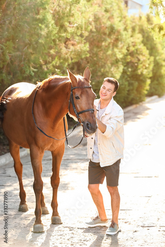 Young man with cute horse outdoors © Pixel-Shot