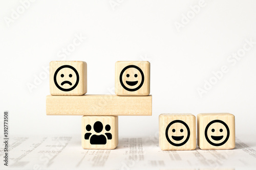 Close up custome choose smiley and sad face icon on wood cube, Service rating, satisfaction concept.
