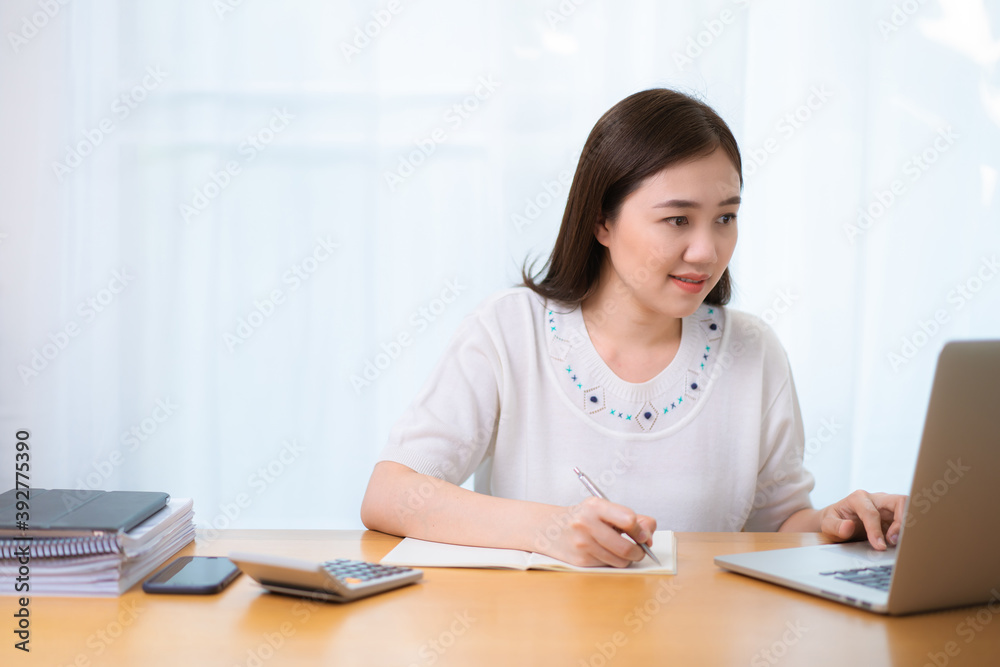 Happy Asian young woman working at home, working from home is the new working solution during the COVID-19 pandemic and able to increase working productivity. Asian beautiful girl using video call. Happy Asian young woman working at home, working from home is the new working solution during the COVID-19 pandemic and able to increase working productivity. Asian beautiful girl using video call.