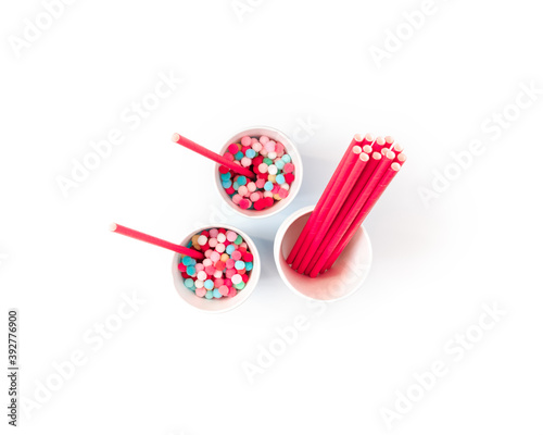 The concept of preparing for a party, event, celebration. Blue paper cups, red straws and colorful balls are on a white background. Template for christmas, new year, invitation, banner. Flat lay.