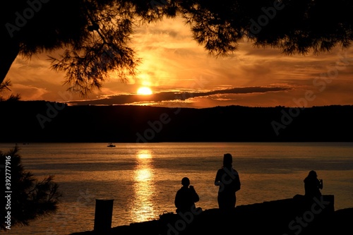 Silhouettes of people on the beach looking the sunset over the sea/ Meditation concept