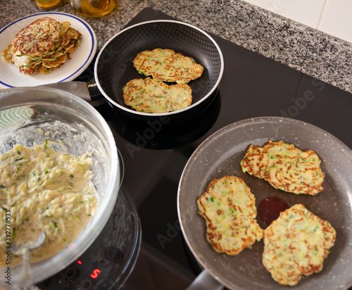 Process of cooking zucchini pancakes on fry pan in home kitchen
