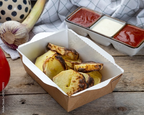 young grilled potatoes in a paper disposable box. served with sauces of your choice.