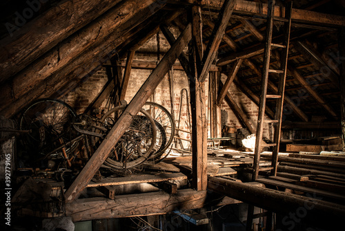 A rusty old vintage bikes in a barn with old farm machinery photo