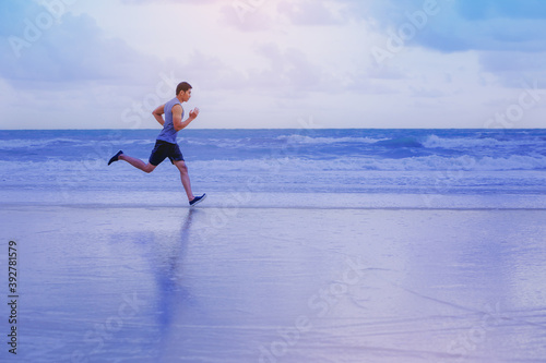 Man running athletes at the beach with sunset background.	