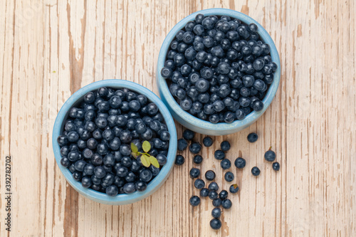 Blueberries in blue bowls on white wooden board background, top view. Healthy eating