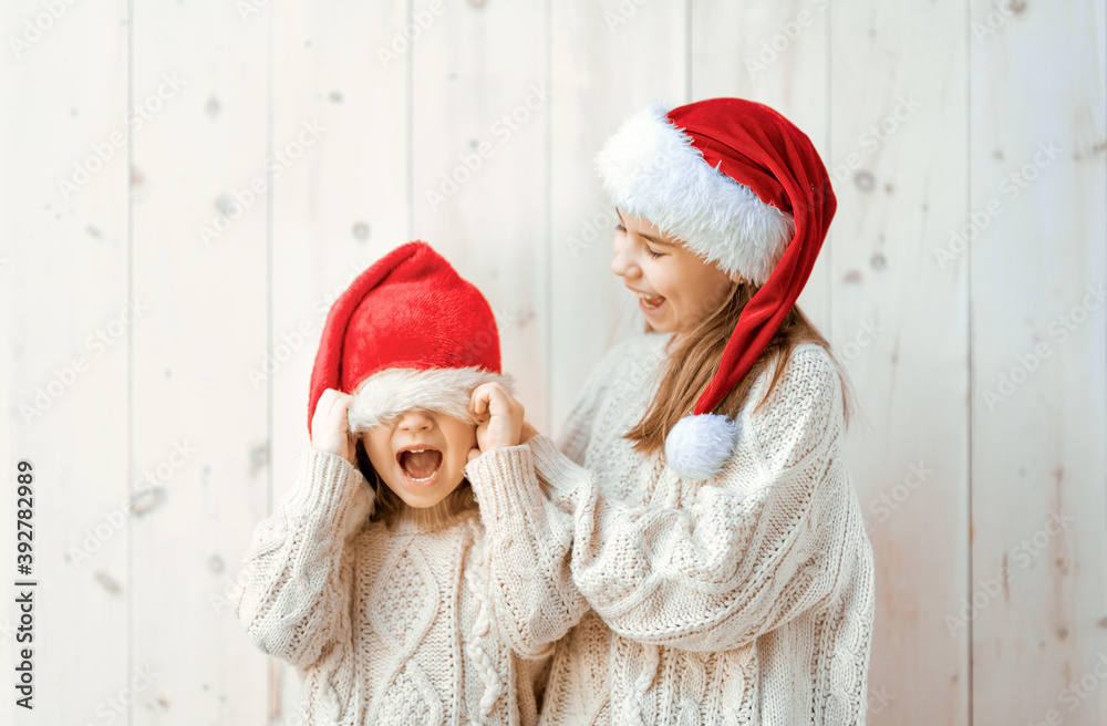 girls in Santa's hats on white wooden background girls in Santa's hats on white wooden background