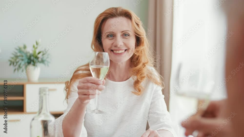 Back view of smiling old Caucasian woman with long ginger hair having dinner with unrecognizable man. People clinking champagne glasses Back view of smiling old Caucasian woman with long ginger hair having dinner with unrecognizable man. People clinking champagne glasses