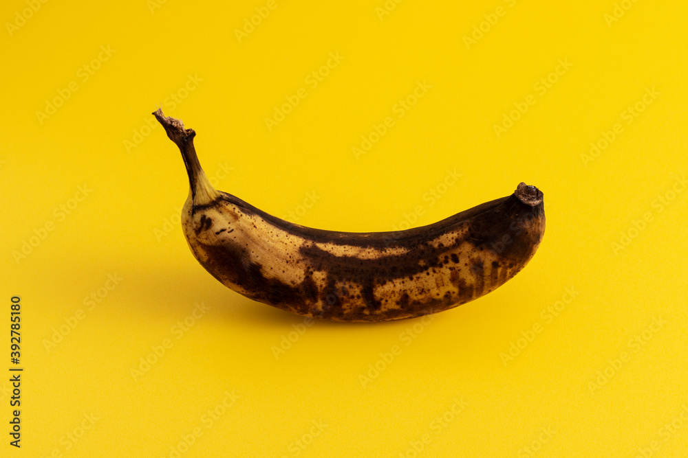 Rotten banana on yellow background. Excessive consumption concept. Rotten banana on yellow background. Excessive consumption concept.