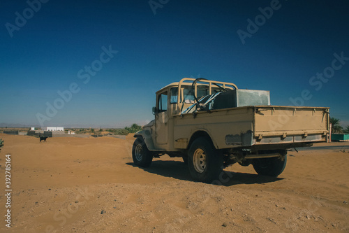 An old jeep standing peacefully on a flat part of a sand dune, close to oasis. Typical arab transporter. © Anze