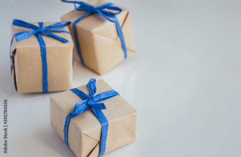 Gift boxes made from craft paper with blue ribbon on white background with copy space. Gift boxes made from craft paper with blue ribbon on white background with copy space.