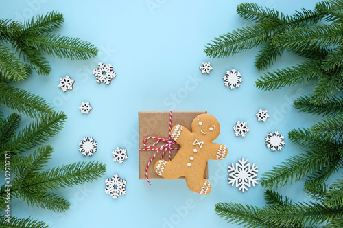 cute gingerbread man, gift box, wooden snowflakes and christmas tree branches on blue background. Christmas and New Year holiday concept. winter festive season. flat lay