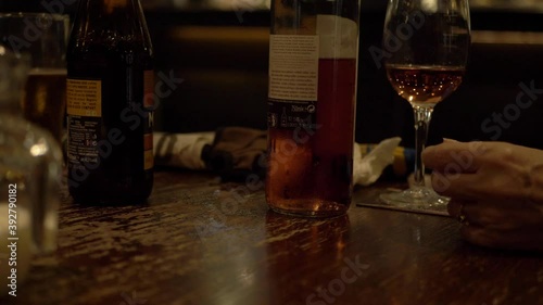 Glasses and bottles of wine and beer with woman's hand medium panning shot photo