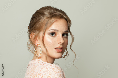 Healthy woman face with freckles on skin and ginger hair on white background.