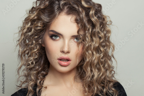 Beautiful model woman with balayage and curly hair on white background portrait