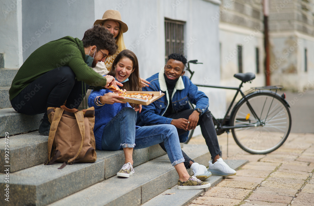Group of young people outdoors in town, eating pizza. Coronavirus concept. Group of young people outdoors in town, eating pizza. Coronavirus concept.