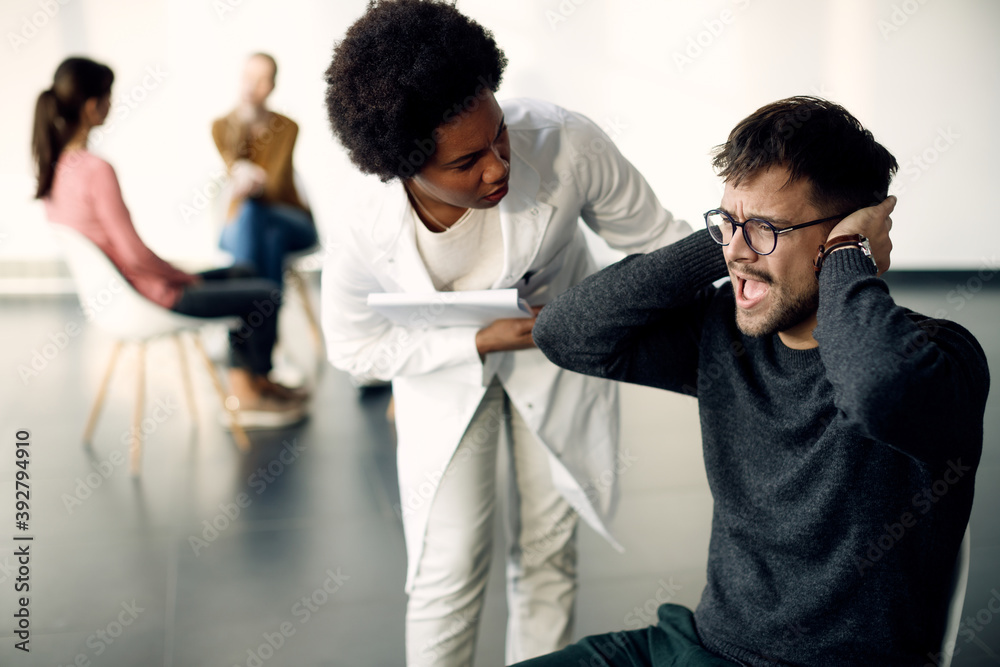 Fototapeta premium Young man screaming while being on group psychotherapy at medical center.