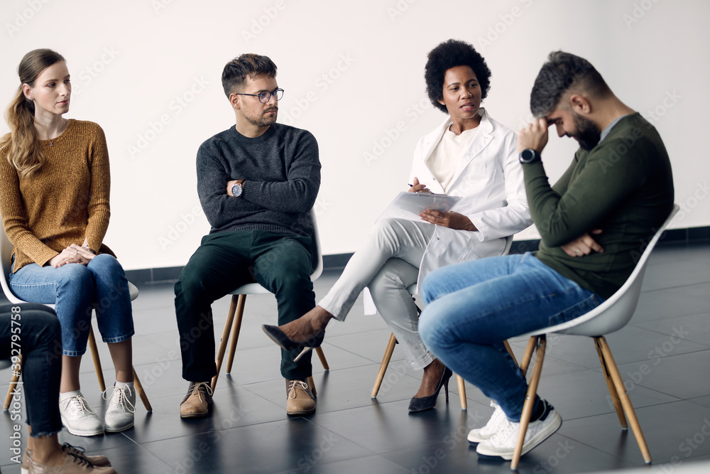 Fototapeta premium African American psychotherapist talking to participants of a group therapy.