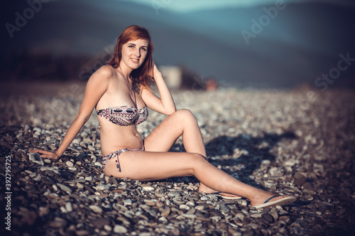 Beautiful young woman enjoing herself on pebble sunny beach