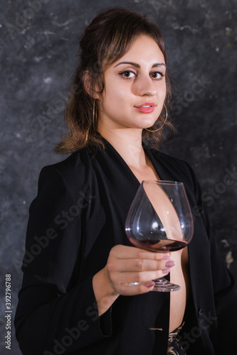 Beautiful young lady in black jacket with glass of wine