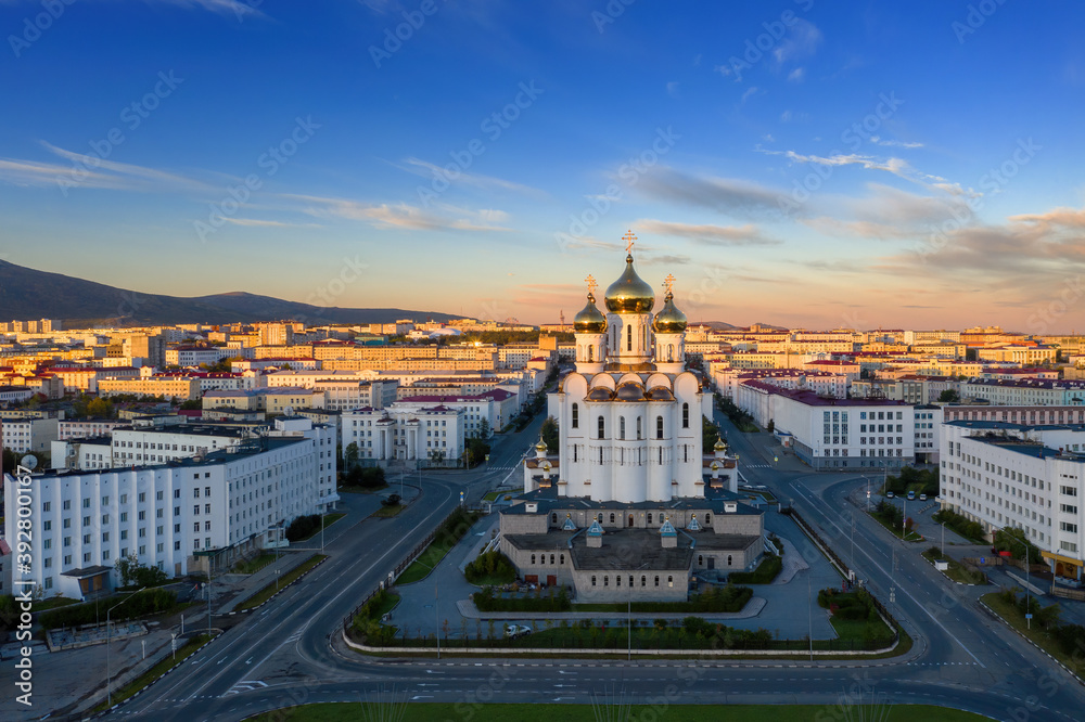 Fototapeta premium Picturesque morning cityscape. Aerial view of the city of Magadan. View of the large cathedral, streets and buildings at sunrise. Holy Trinity Cathedral, Magadan, Magadan Region, Far East of Russia.