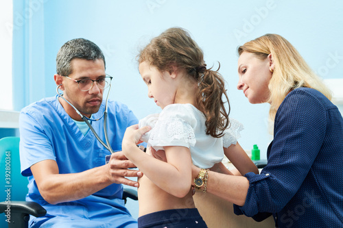 Pedeatrician african doctor examining little girl with stethoscope photo