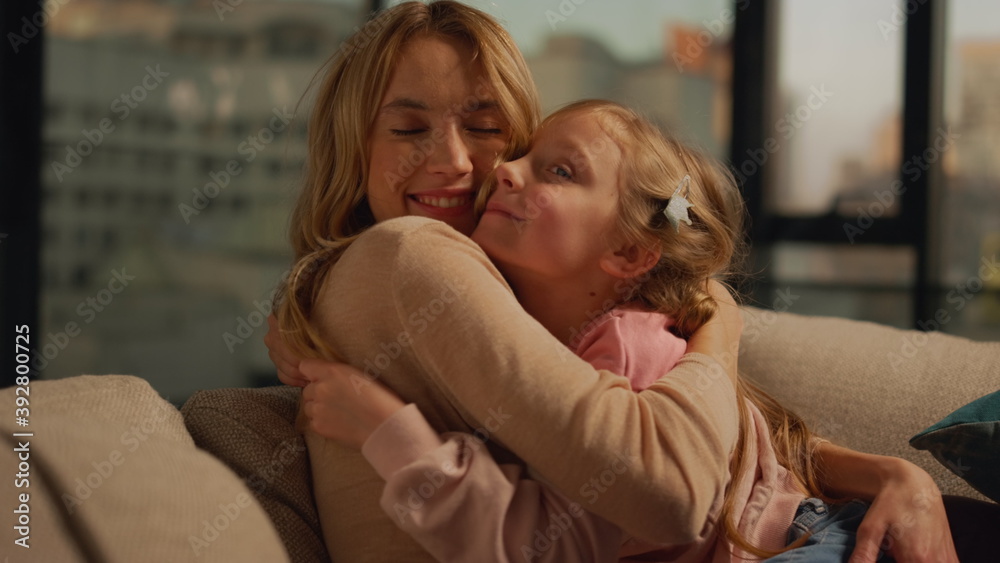 Cheerful mother and daughter kissing at home. Mom and kid spending time indoors. Cheerful mother and daughter kissing at home. Mom and kid spending time indoors.