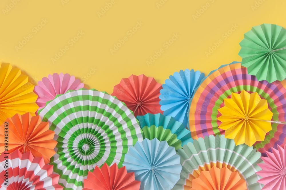 Colorful paper rosette and birthday garlands. Decorating for a party. Round, bright and color decoration. Yellow background.