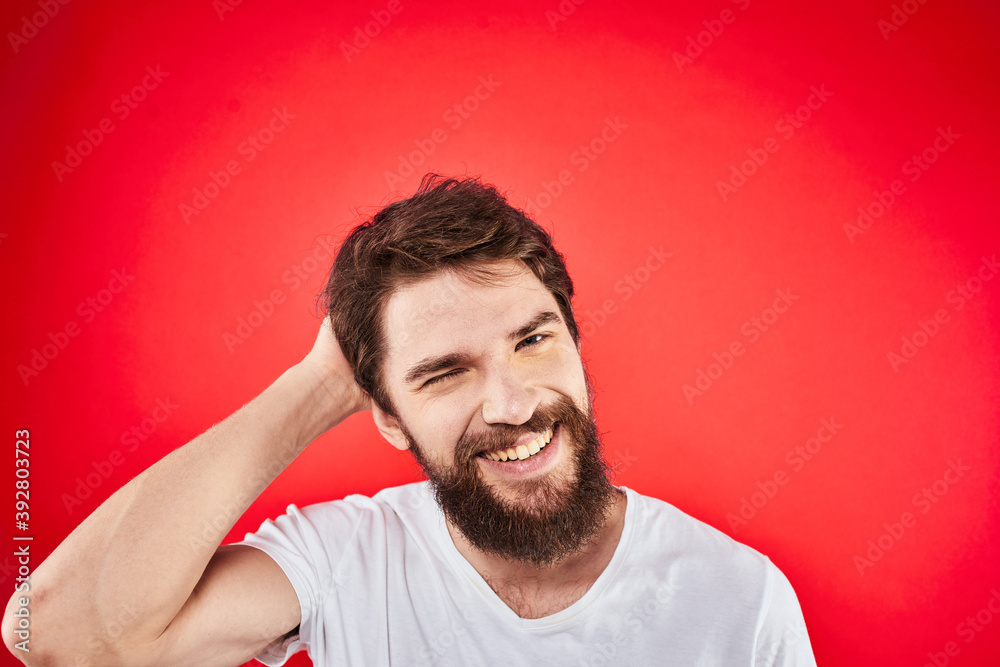A man in a white T-shirt with a beard gestures with his hands emotions red background A man in a white T-shirt with a beard gestures with his hands emotions red background