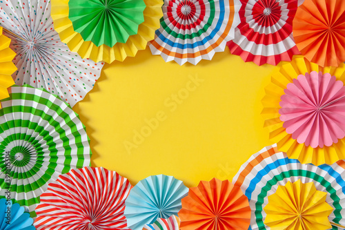 Colorful paper rosette and birthday garlands. Decorating for a party. Round  bright and color decoration. Yellow background.