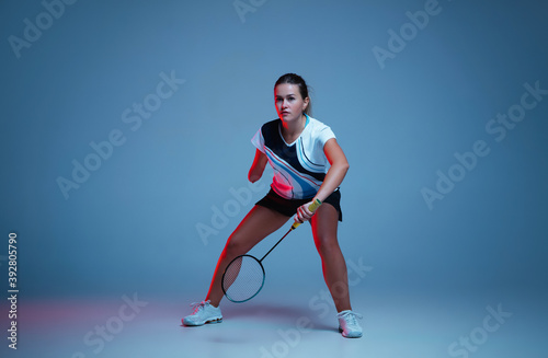 Fototapeta Naklejka Na Ścianę i Meble -  Beautiful handicap woman practicing in badminton isolated on blue background in neon light. Lifestyle of inclusive people, diversity and equility. Sport, activity and movement. Copyspace for ad.