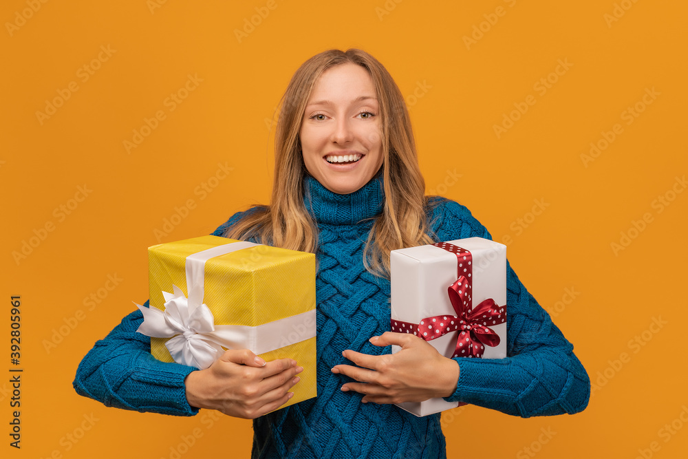 Charming young woman holding a lot of gift boxes. Studio shot, yellow background. New Year, Birthday, Holiday concept Charming young woman holding a lot of gift boxes. Studio shot, yellow background. New Year, Birthday, Holiday concept