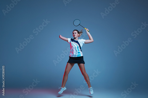 Beautiful handicap woman practicing in badminton isolated on blue background in neon light. Lifestyle of inclusive people, diversity and equility. Sport, activity and movement. Copyspace for ad.