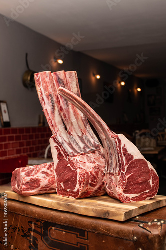 Tomahawk Steaks dryaged auf Holzbrett im Restaurant mit Metrofliesen photo