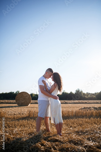 Attractive woman posing in the mown wheat fields with a sheaf in the village. Hay bales on the field after harvest, a place for a photo session of a beautiful Slavic couple © Дмитрий Ткачук